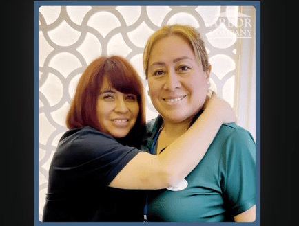 two female staff members hugging and smiling