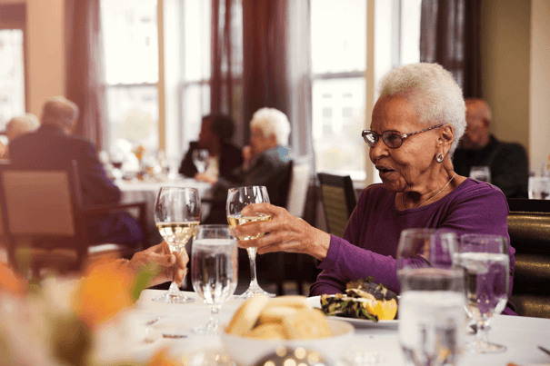 Resident holding her glass while dining