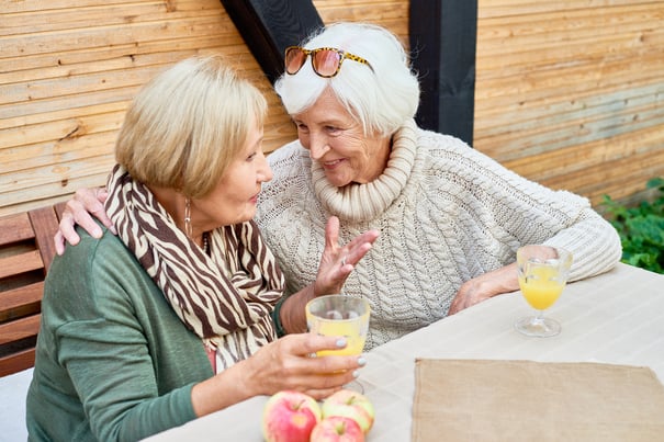Two residents enjoy drinks and conversation on an outdoor deck, embracing the active senior lifestyle and outdoor amenities of North Shore senior living in Glenview.