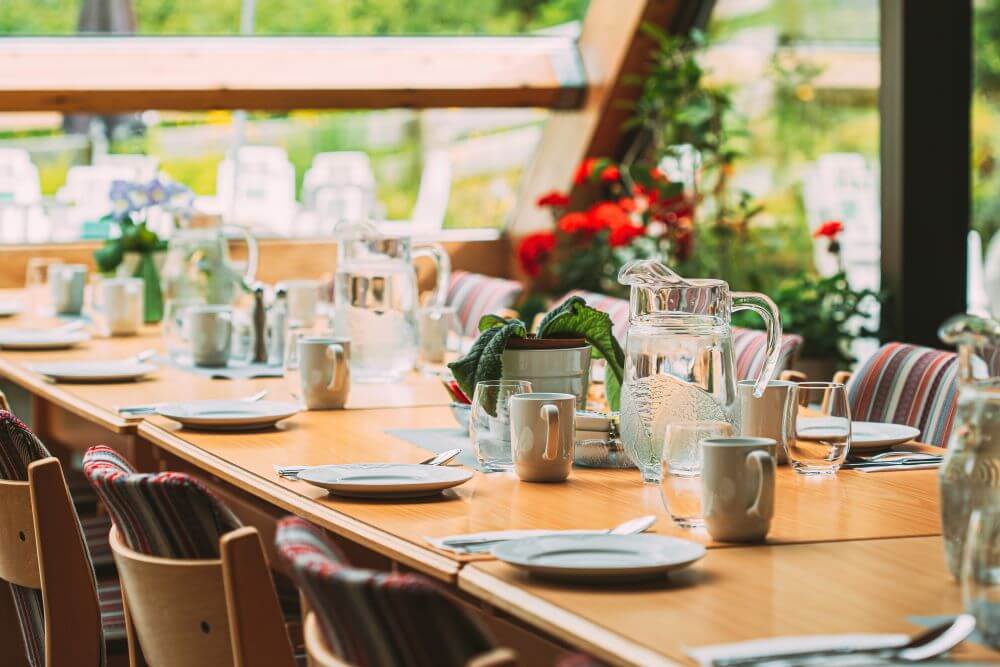 An elegantly set dining table with fresh flowers and sparkling glassware overlooks a garden view, reflecting the senior living with gourmet dining North Shore residents enjoy at this top-rated senior living Glenview community.