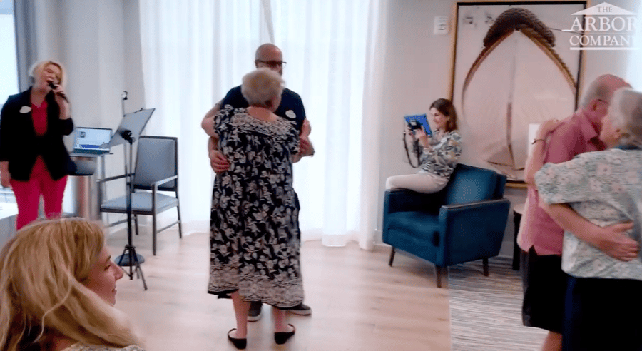 Residents dance together while a staff member sings live during a music activity at Mirabelle's memory care neighborhood in Miami, FL, where engaged programming keeps residents active, joyful, and connected.