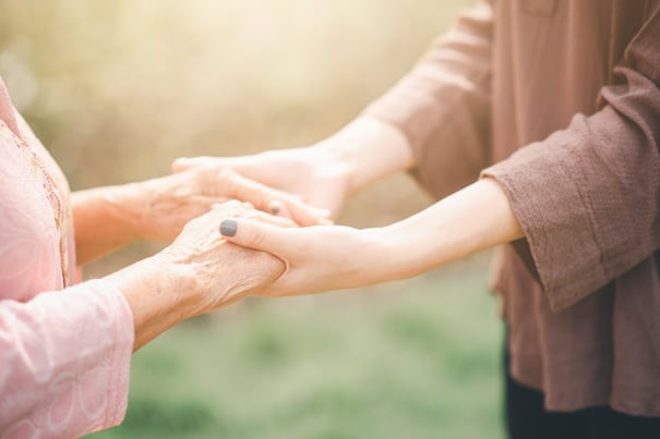 A close-up of two people gently holding hands outdoors, capturing the warmth and compassionate support at the heart of memory care in Suwanee, GA.