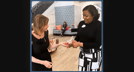 A staff member warmly presents a small gift to a resident in the bright, welcoming lobby, reflecting the thoughtful, personalized senior care Marietta GA families appreciate at our senior living East Cobb community.