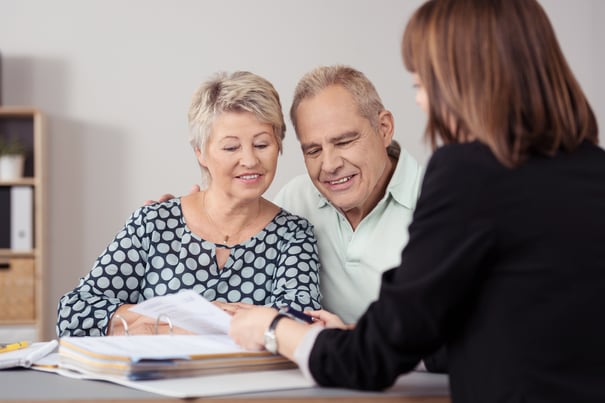 a senior couple discussing paperwork with a female staff member