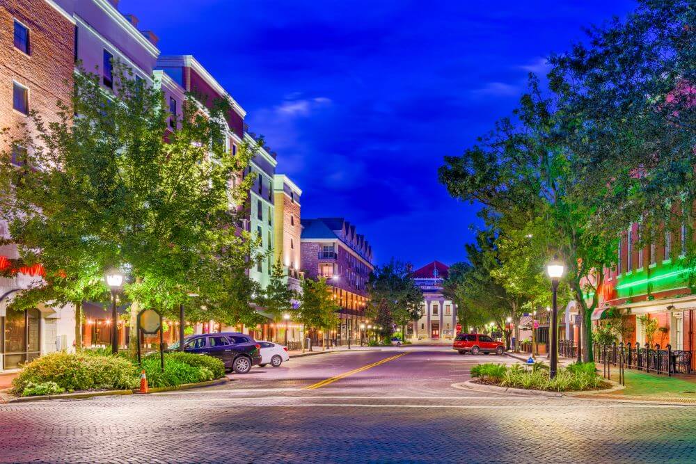 A vibrant evening streetscape with illuminated storefronts and tree-lined sidewalks near this Glenview senior living community, capturing the charm of senior living near The Glen Town Center, a top-rated senior living Glenview destination.