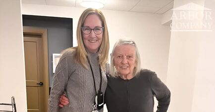 Two women in gray shirts with arms around each others shoulders