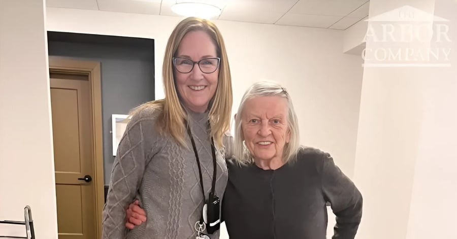 Two women in gray shirts with arms around each others shoulders