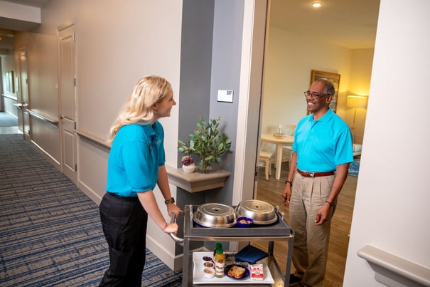 A staff member and resident share a warm exchange in a well-kept hallway, reflecting the friendly, attentive service available to seniors near Acworth, GA.