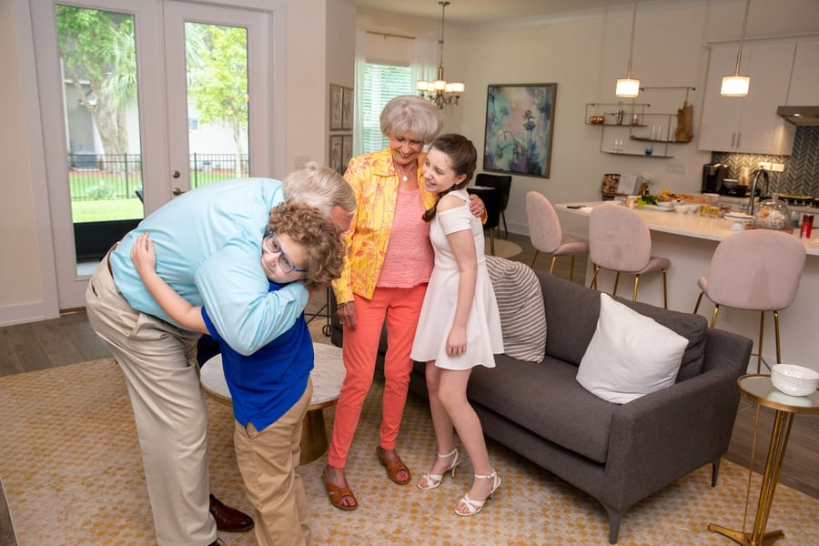 A family shares an affectionate embrace and laughter in a bright, welcoming home, reflecting the active senior lifestyle found through Glenview senior living.