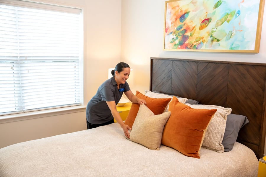 a female staff member arranging pillows on a bed