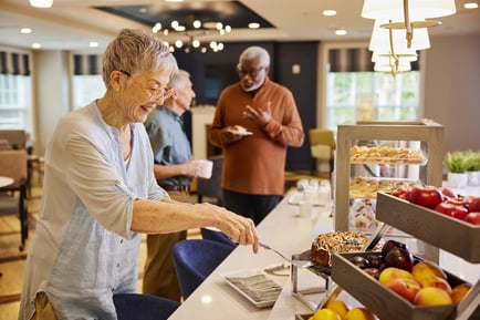 Older adults enjoy a beautifully stocked dining spread in a bright, elegantly appointed dining area, reflecting the resort-style senior living experience at Arbor Terrace Morris Plains, NJ.