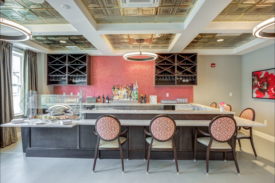 An elegant wet bar and dining area with wine displays and cozy seating highlight the gourmet dining found within memory care communities in Glenview, IL.