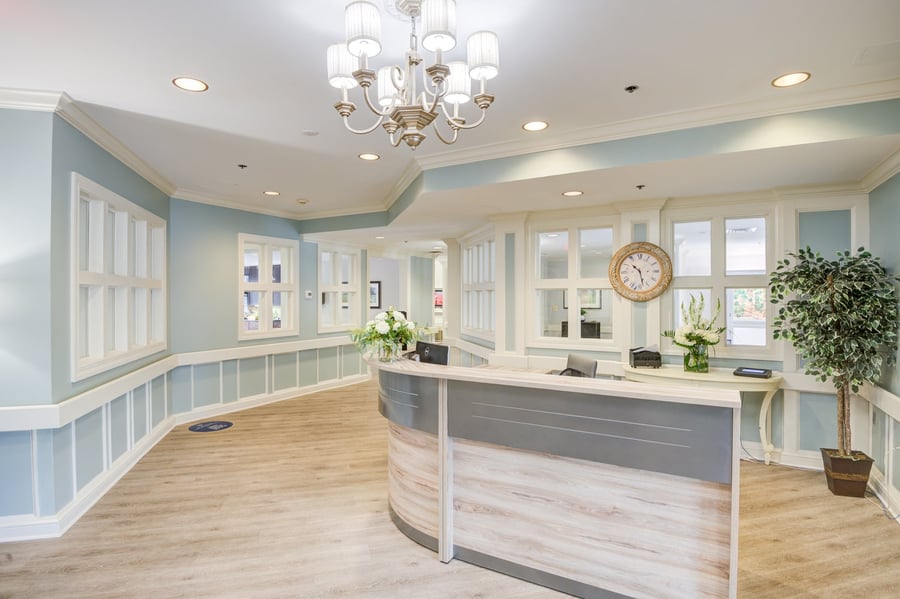 a calm, spacious senior living community lobby with wooden floors and light-blue walls
