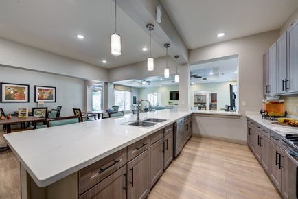 A bright, modern kitchen and dining area at Arbor Terrace Lakeway featuring a large island, pendant lighting, and open views — part of the best senior living community Lakeway TX.
