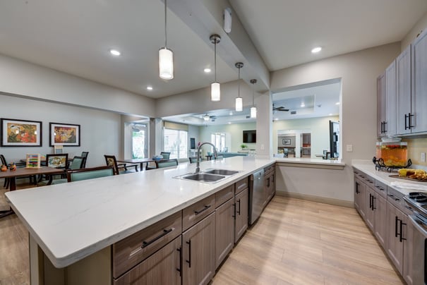 A bright, modern kitchen and dining area at Arbor Terrace Lakeway featuring a large island, pendant lighting, and open views — part of the best senior living community Lakeway TX.