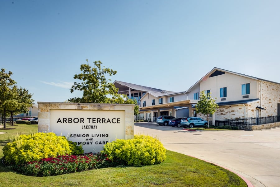 The exterior of Arbor Terrace Lakeway on a sunny day, with its stone monument sign reading 