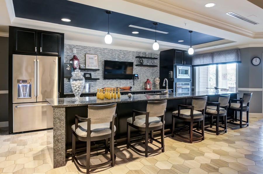 A beautifully appointed kitchen and bar area at Arbor Terrace Morris Plains features granite countertops, pendant lighting, and stainless steel appliances, reflecting the upscale, resort-style senior living in Morris Plains, NJ.