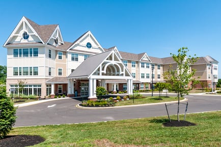 The welcoming exterior of Arbor Terrace Mount Laurel, a beautifully landscaped senior community offering dementia care and assisted living in Mount Laurel NJ under a bright blue sky.