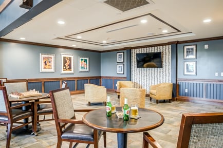 A cozy lounge area with warm lighting, framed artwork, and comfortable seating at Arbor Terrace Mountainside, reflecting the welcoming atmosphere residents enjoy at this assisted living community in NJ.