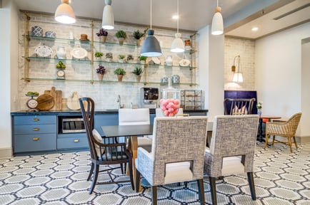 A stylishly designed dining area features open glass shelving, pendant lighting, blue cabinetry, and mixed seating, reflecting the upscale, restaurant-style atmosphere at our senior living East Cobb and assisted living Marietta GA community.