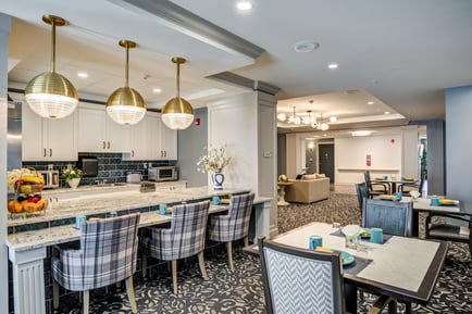 A elegantly designed dining area featuring gold pendant lights, marble countertops, and stylish seating, showcasing the upscale dining experience at our senior living community in Gambrills, MD.