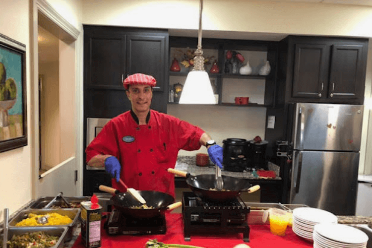 A chef cooks fresh dishes in a stylish open kitchen, showcasing the inviting dining experience at senior living in Citrus Park, FL.