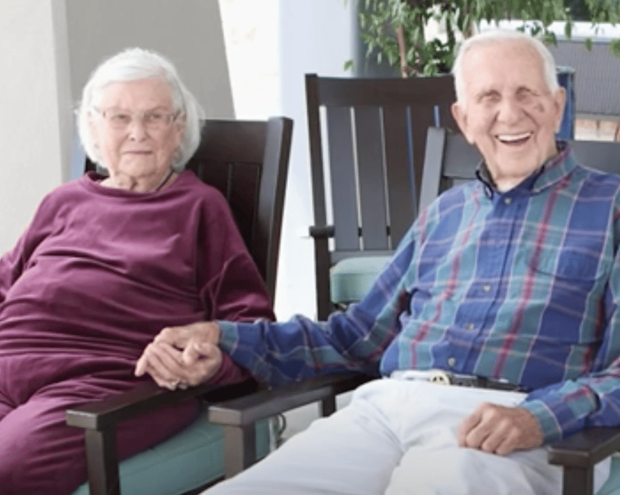 Two older adults sit side by side holding hands in a bright, comfortable space at Arbor Terrace Lakeway — personalized assisted living Lakeway TX built on connection and engagement.