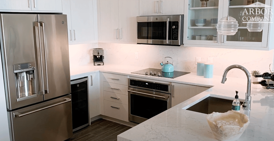 A fully equipped modern kitchen with stainless steel appliances, white cabinetry, and marble countertops in an independent living apartment at Mirabelle, a premier senior living community in Miami, FL.