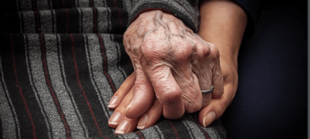 A younger hand tenderly holds an elder's hand, symbolizing the compassionate Alzheimer's care and dedicated memory care support available in Suwanee, GA.