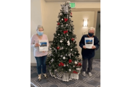 Two senior ladies posing beside the christmas tree
