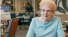 A smiling resident seated in the dining room at Arbor Terrace Highland Park, a senior living community in Highland Park, IL.