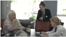 A staff member attentively serving residents at Arbor Terrace Lakeway, capturing the warm and personalized care that defines daily life in this assisted living Lakeway TX community.