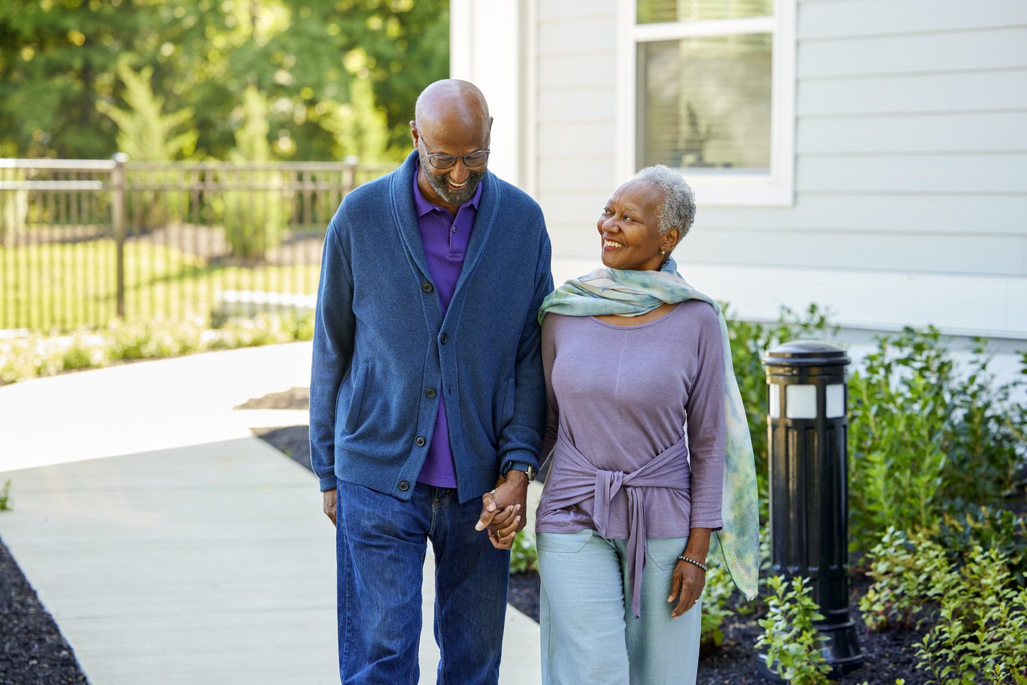 Senior couple holding hands walking outside on sidewalk area