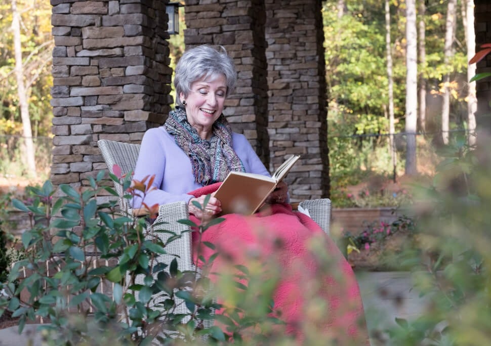 Senior woman reading a book at outdoor terrace at Arbor